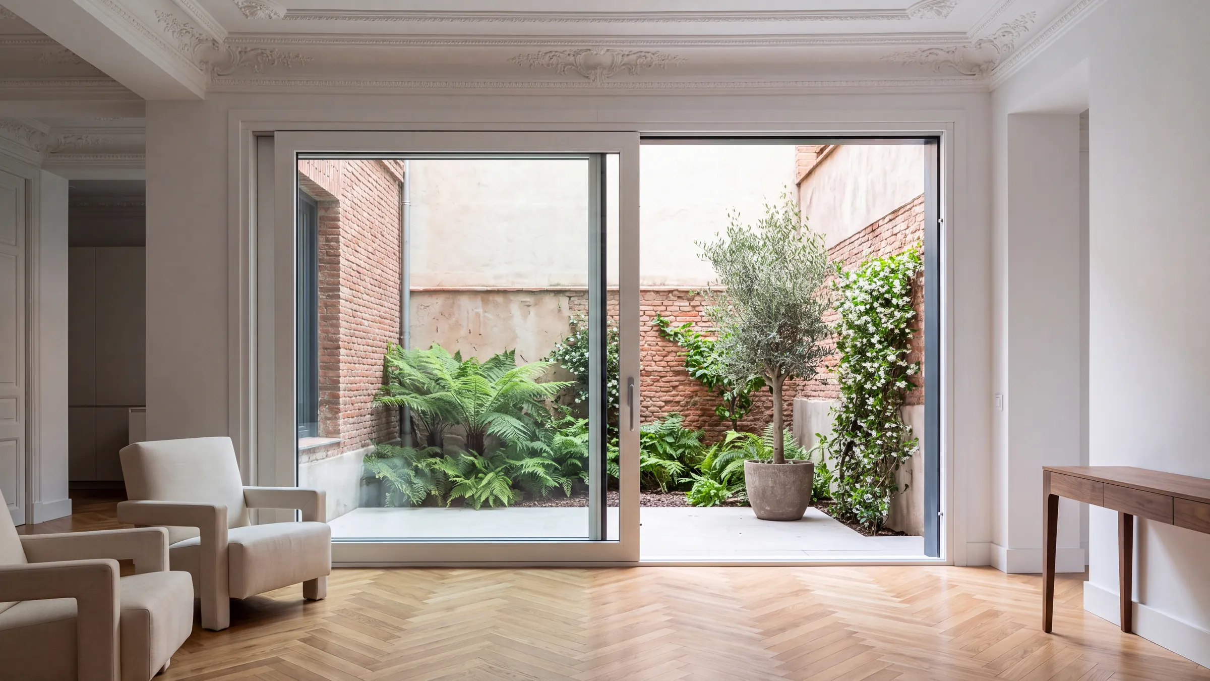 Salón de un piso señorial reformado, de techos altos, con una corredera grande abierta a un patio interior ajardinado