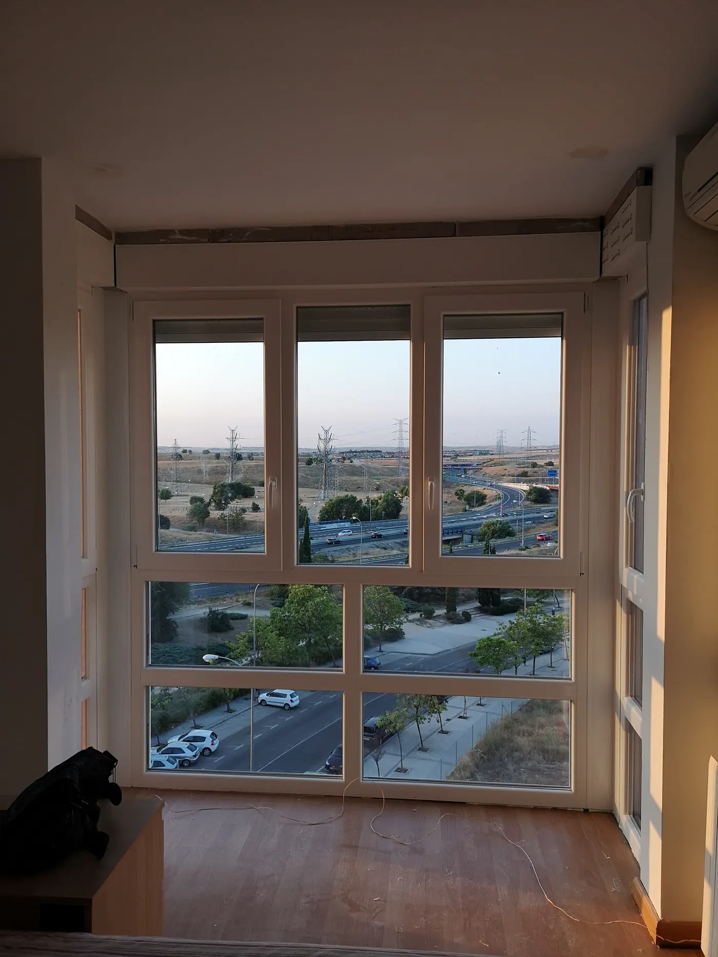 Esquina de un piso cerrada con un paño blanco de PVC que va del suelo al techo: practicables arriba, fijos abajo y un lateral acristalado