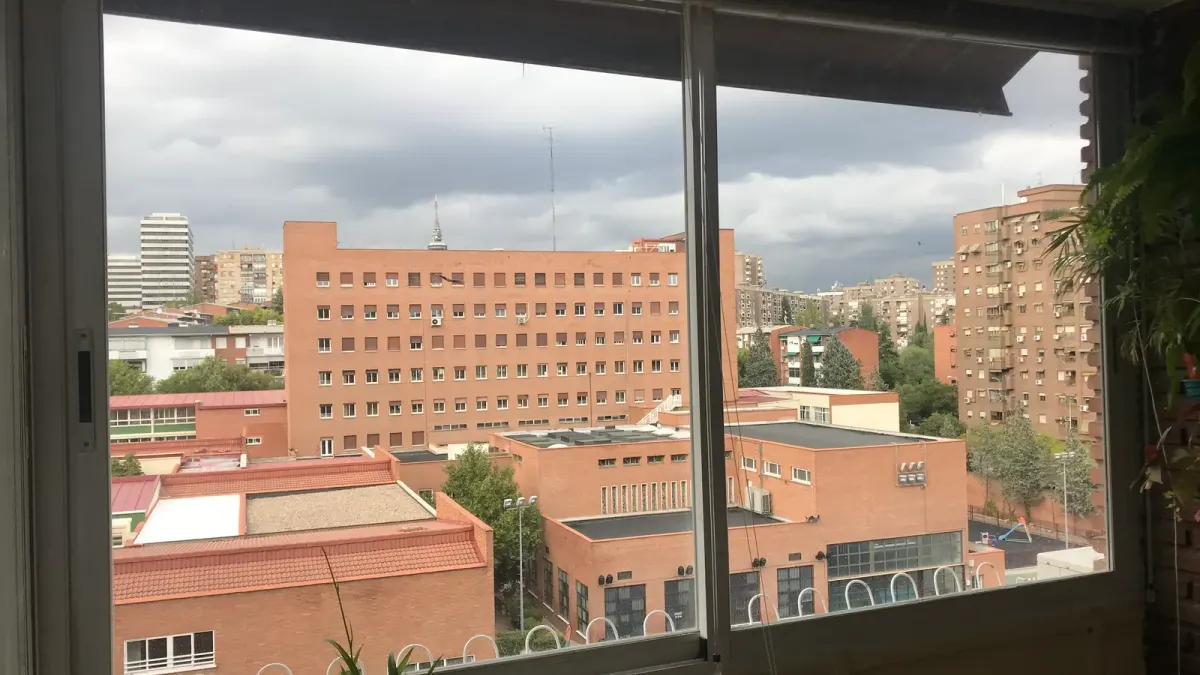 Ventana corredera antigua de aluminio de dos hojas con vistas a edificios de ladrillo