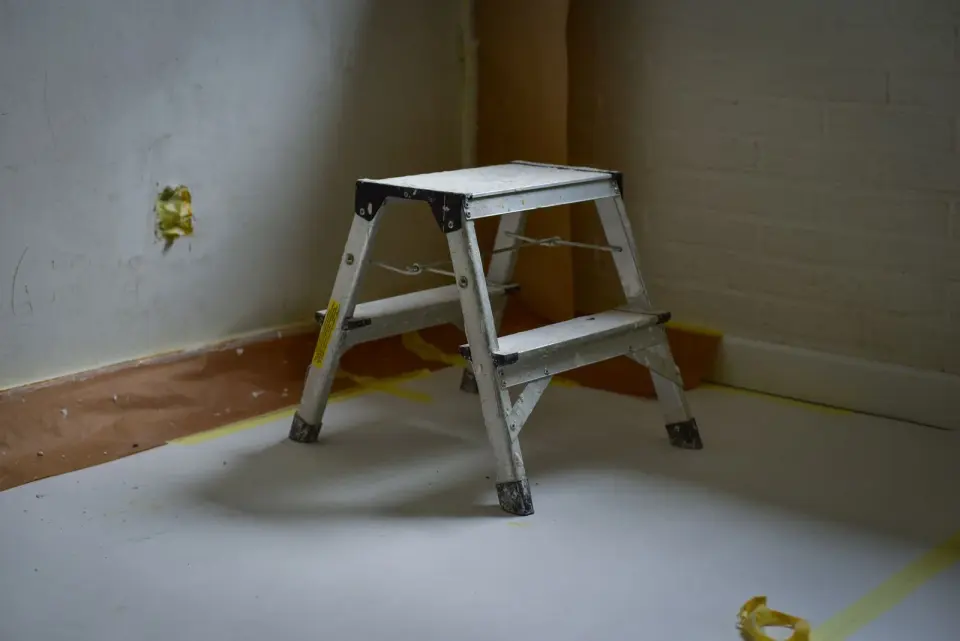 Escalera de tijera de aluminio de dos peldaños abierta en una habitación vacía