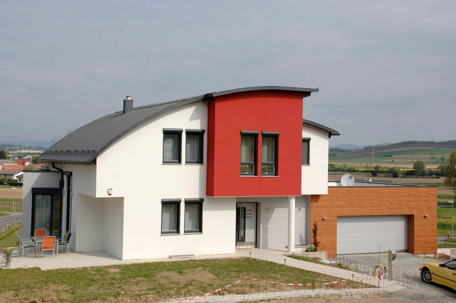 Vivienda unifamiliar blanca con un volumen rojo y ventanas oscuras