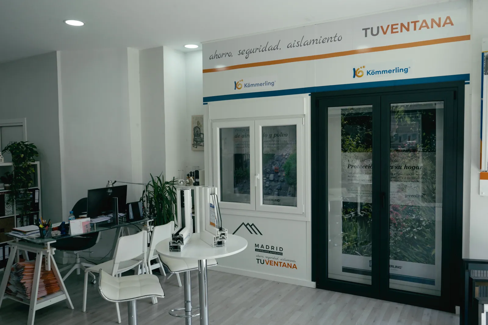 Exposición de la tienda Tu Ventana Madrid con una ventana blanca de PVC, una balconera gris antracita y cortes de perfil Kömmerling sobre una mesa