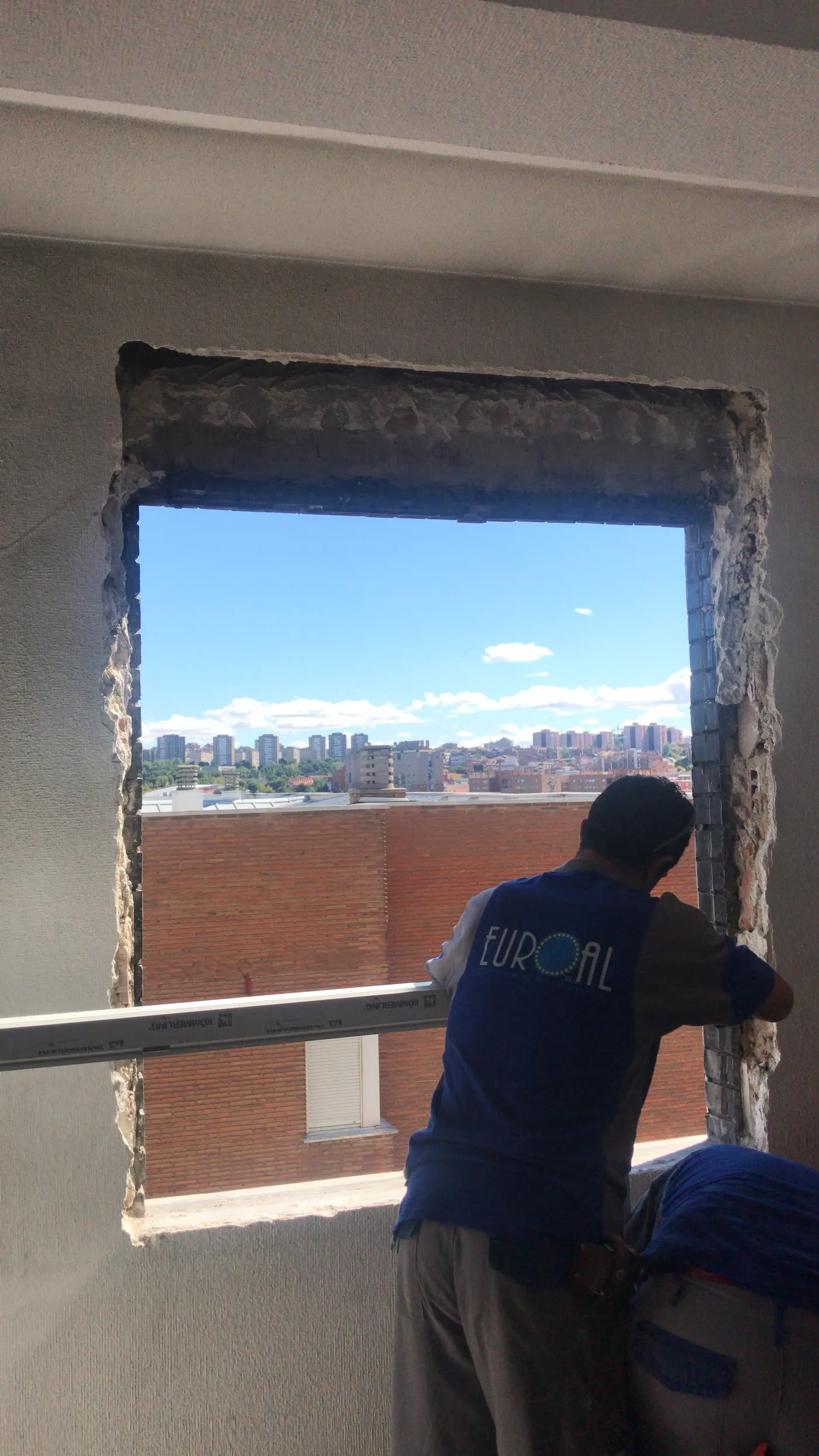 Instalador de Tu Ventana Madrid, de espaldas, retirando una ventana antigua con el hueco ya abierto a la calle