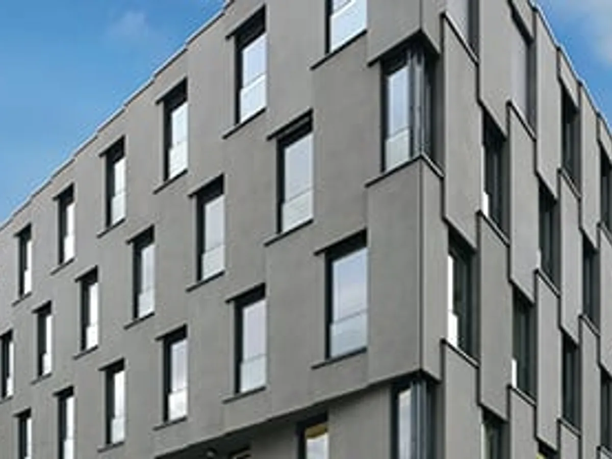 Edificio de viviendas con fachada gris y ventanas en serie