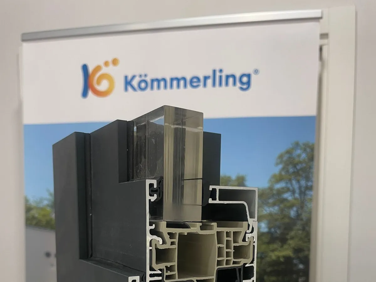 Muestra del perfil AluNext vista de lado, delante de un expositor de Kömmerling